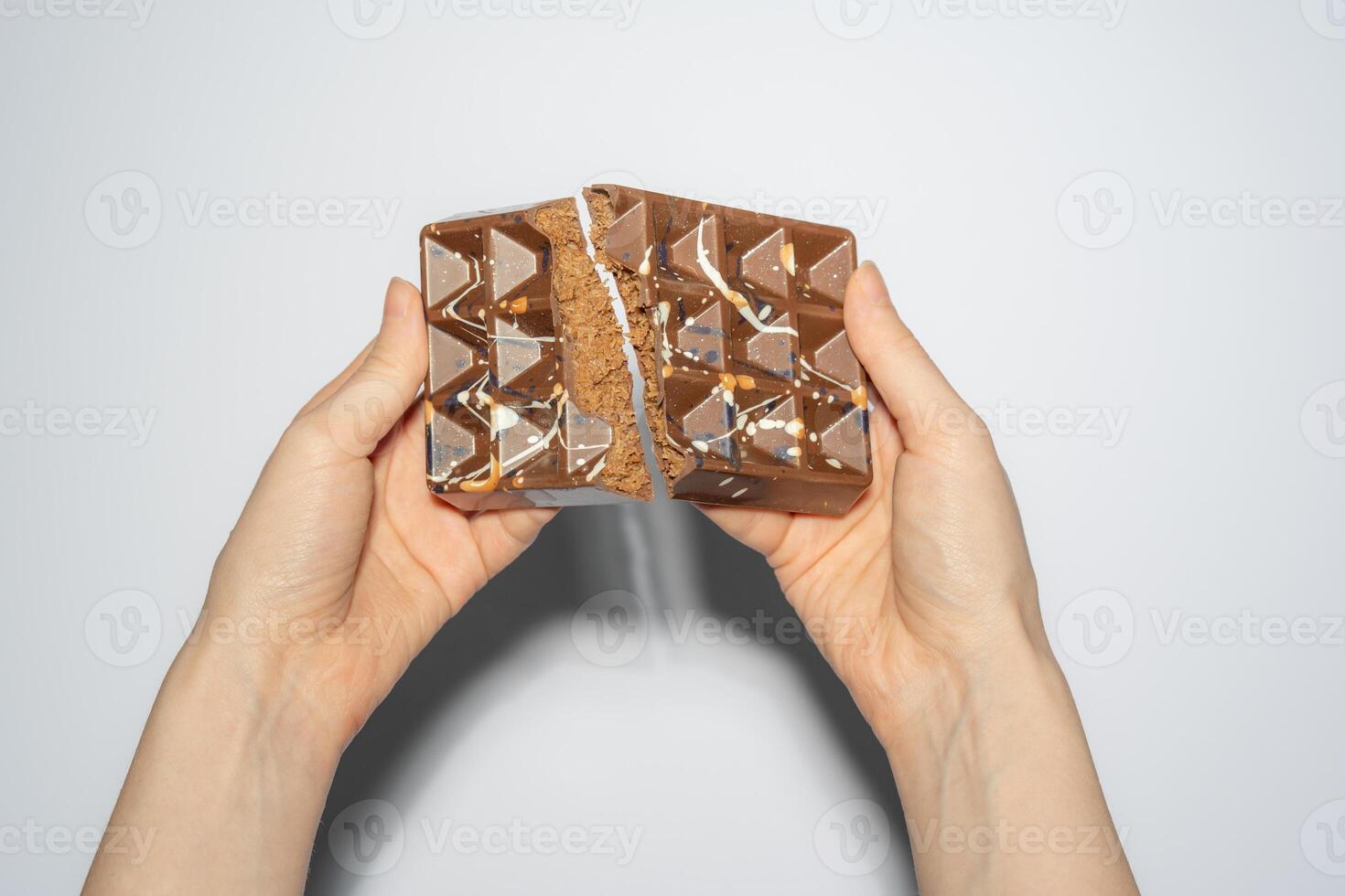Famous Dubai chocolate with chocolate spread and kataifi filling broken in woman's hands. Confectionery handmade sweets, chocolatier. photo