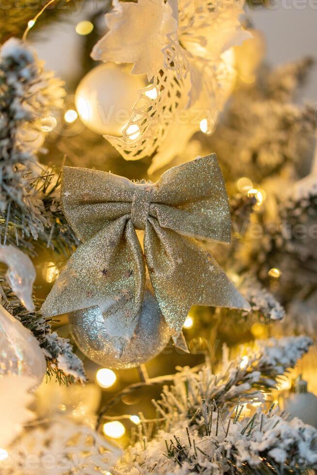 Snow-covered Christmas tree with gold bow Christmas decorations close-up with warm lights. Decorations for the New Year and Christmas photo