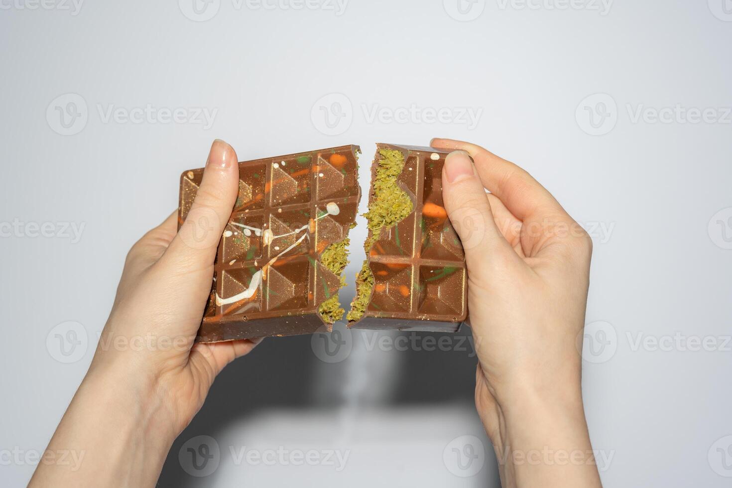 Famous Dubai chocolate with pistachio, tahini and kadaif broken in woman's hands. Confectionery handmade sweets, chocolatier photo