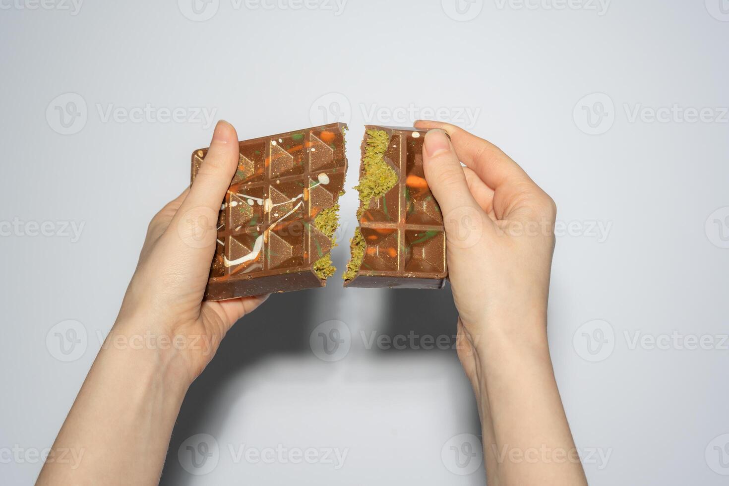 Famous Dubai chocolate with pistachio, tahini and kadaif broken in woman hands. Confectionery handmade sweets, chocolatier photo