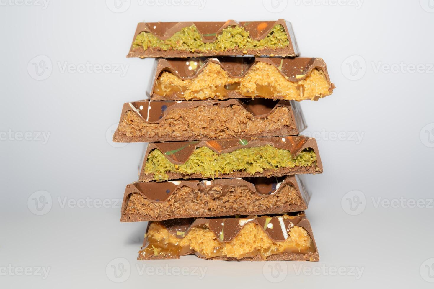 Stack of Trend Dubai chocolate with pistachio, peanut butter, caramel, chocolate spread and kataifi dough. Different flavours. Traditional confectionery. photo