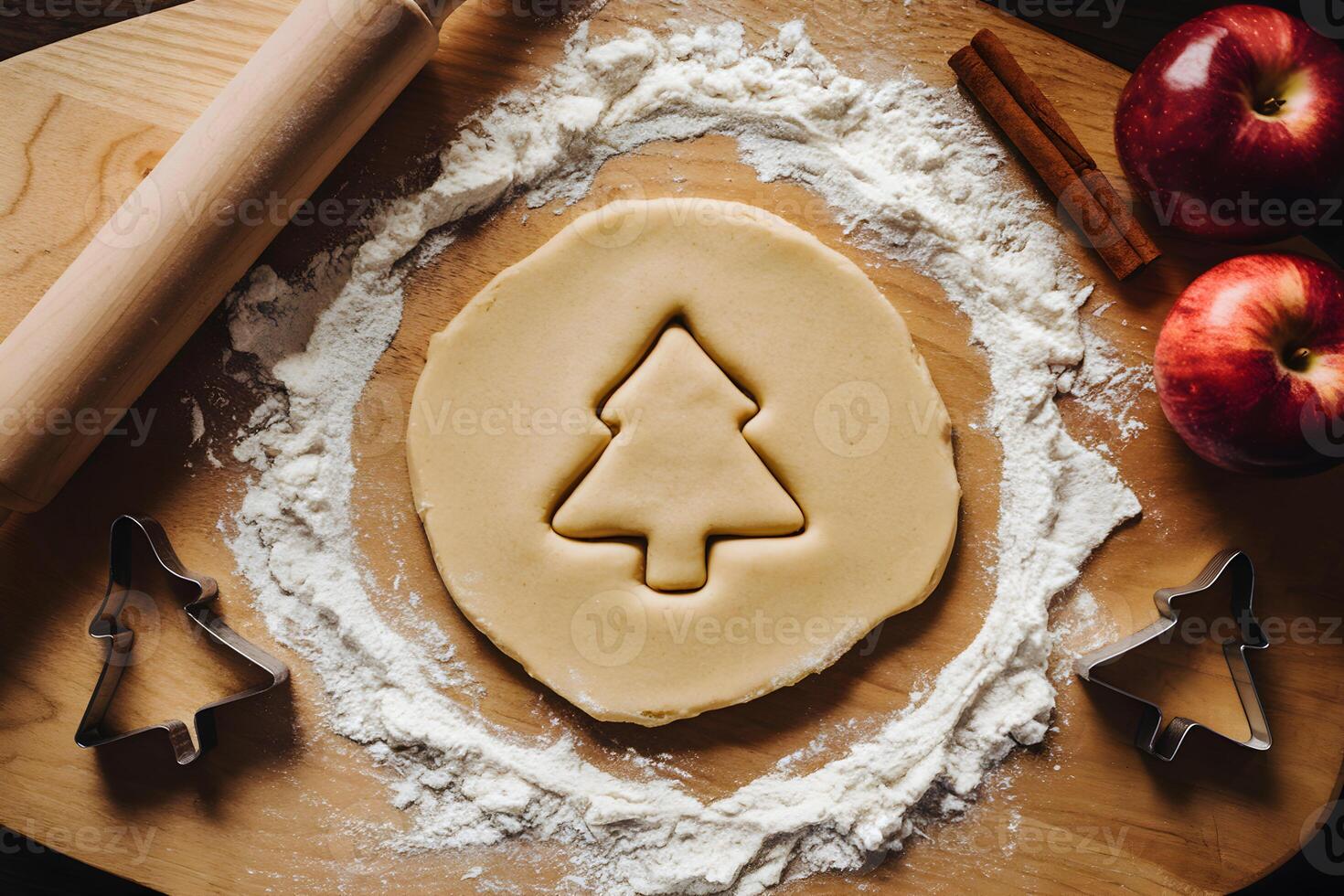 Dough on a floured board with apples, cinnamon, and cookie cutters for baking photo
