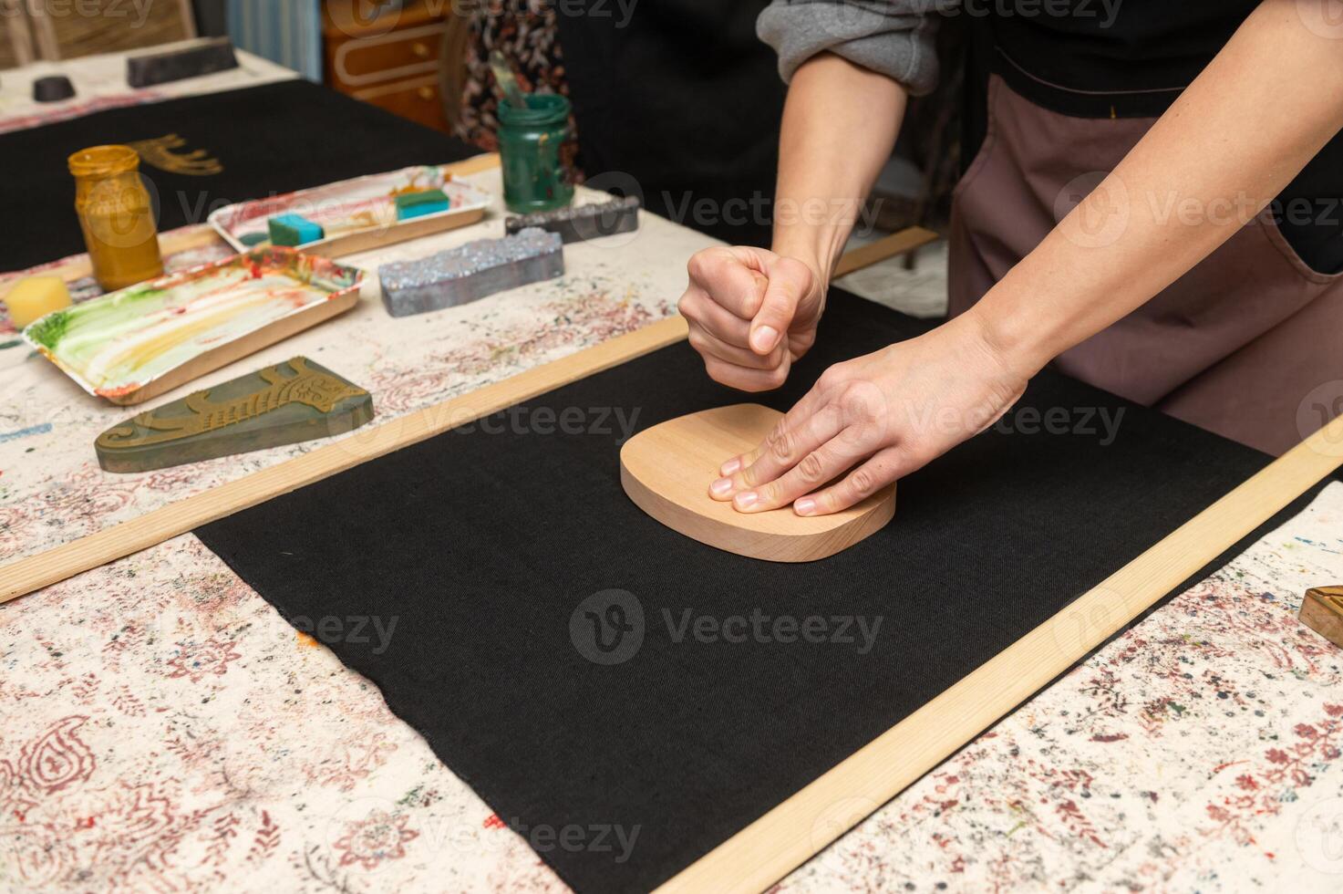 Female artisan printing on fabric with wooden block in craft studio photo