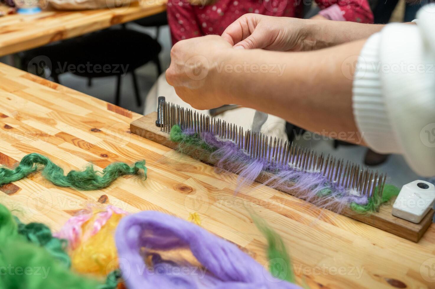 Caucasian female adult preparing wool fibers for weaving on wooden carding board photo