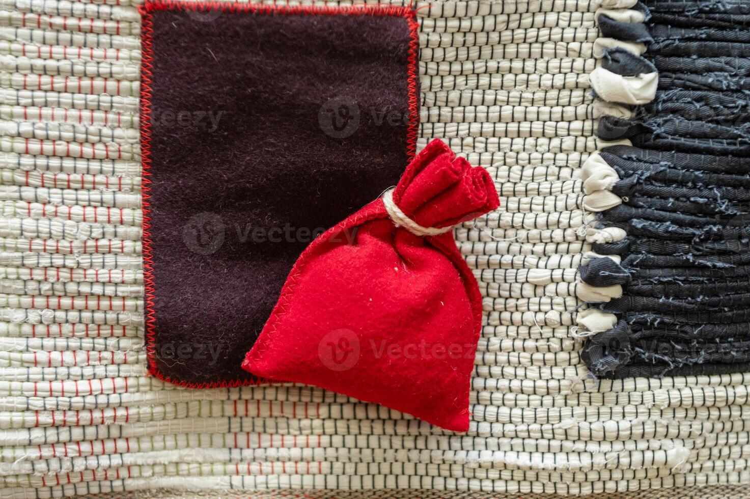 Red fabric pouch on woven textured surface with black and white accents photo