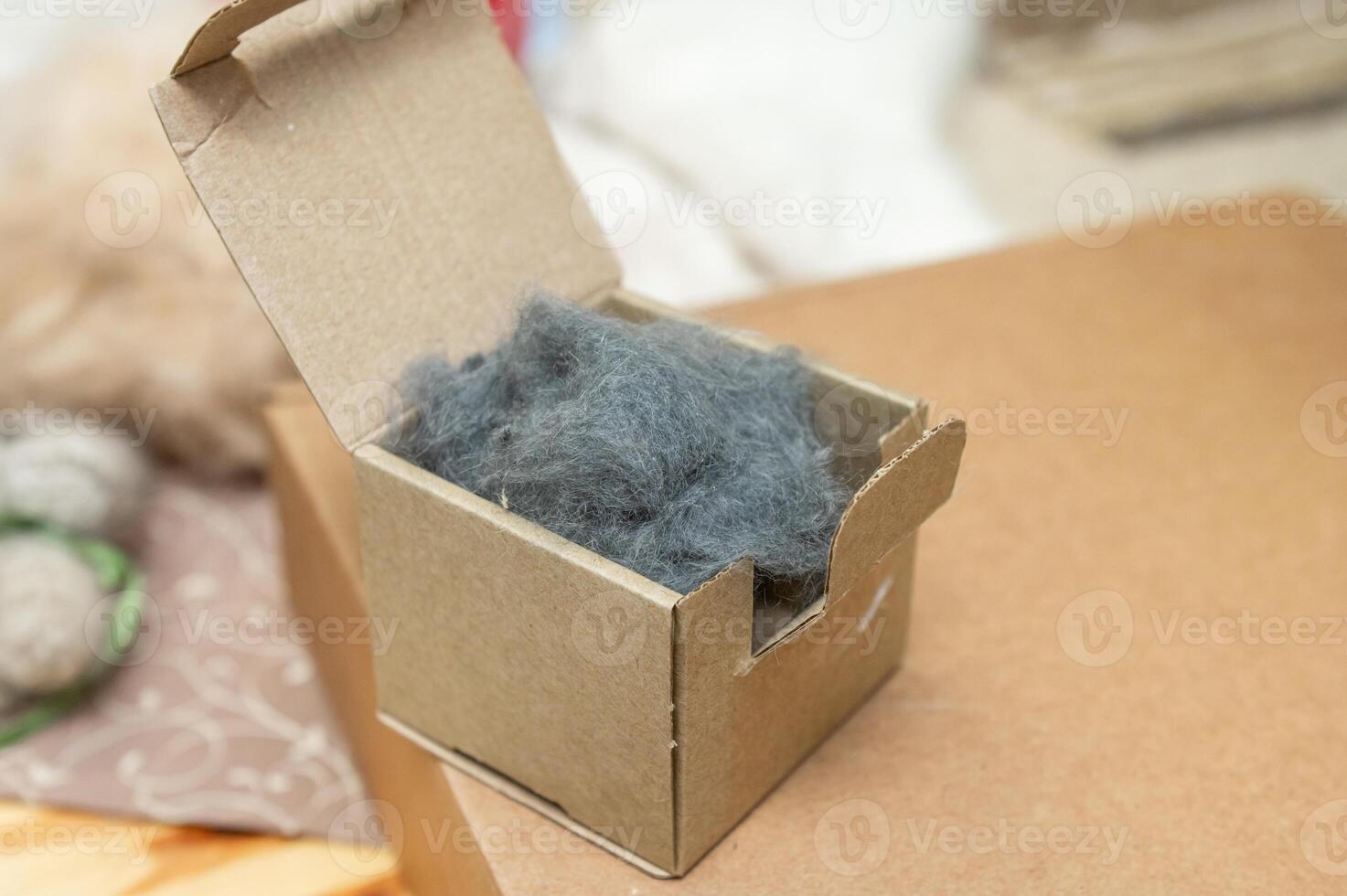 Small cardboard box with fluffy grey material on a table photo