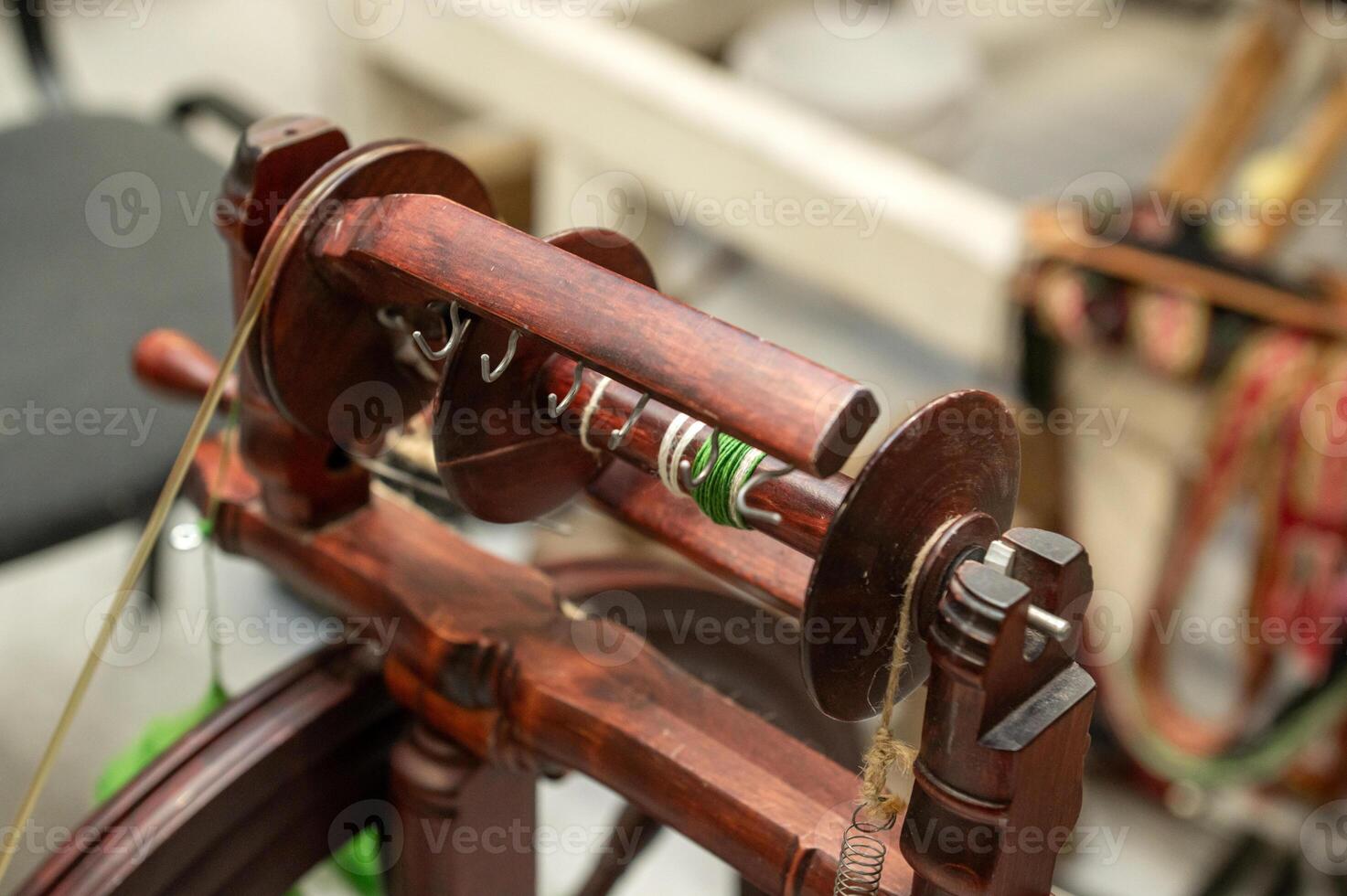 Distaff Day Wooden spinning wheel with yarn and hooks in workshop setting photo