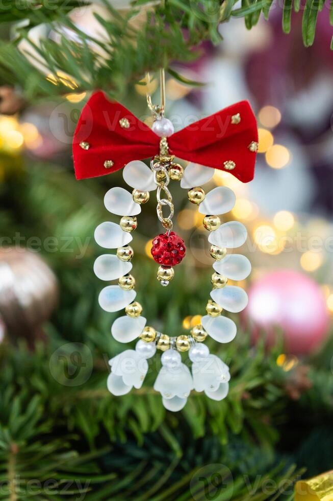 Festive christmas tree ornament with beads and red bow hanging on branch photo