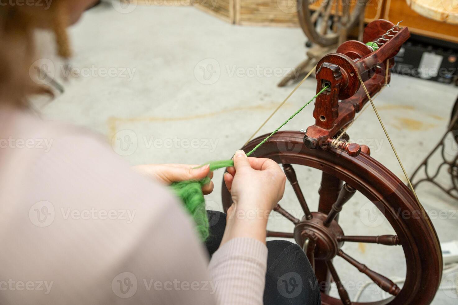 Distaff Day Caucasian female adult spinning yarn on traditional wheel in workshop photo