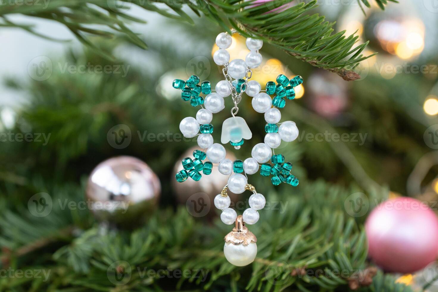 Handmade beaded snowflake ornament hanging on christmas tree photo