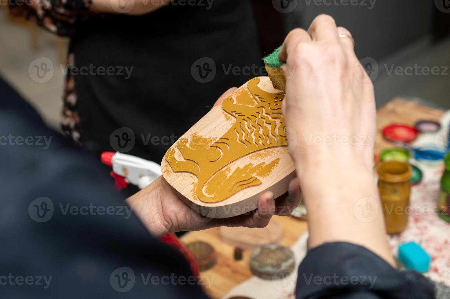 Asian craftsman carving intricate fish design on wooden block photo