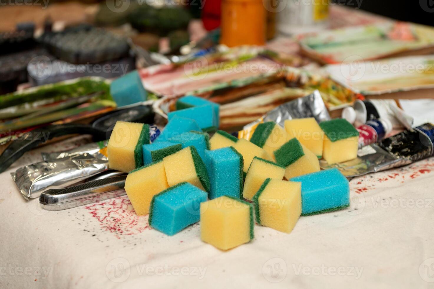 Pile of colorful cleaning sponges on a table amidst artistic supplies photo