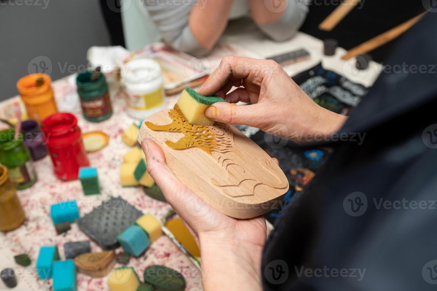 Hands crafting with wooden stamp and sponges in creative workshop photo