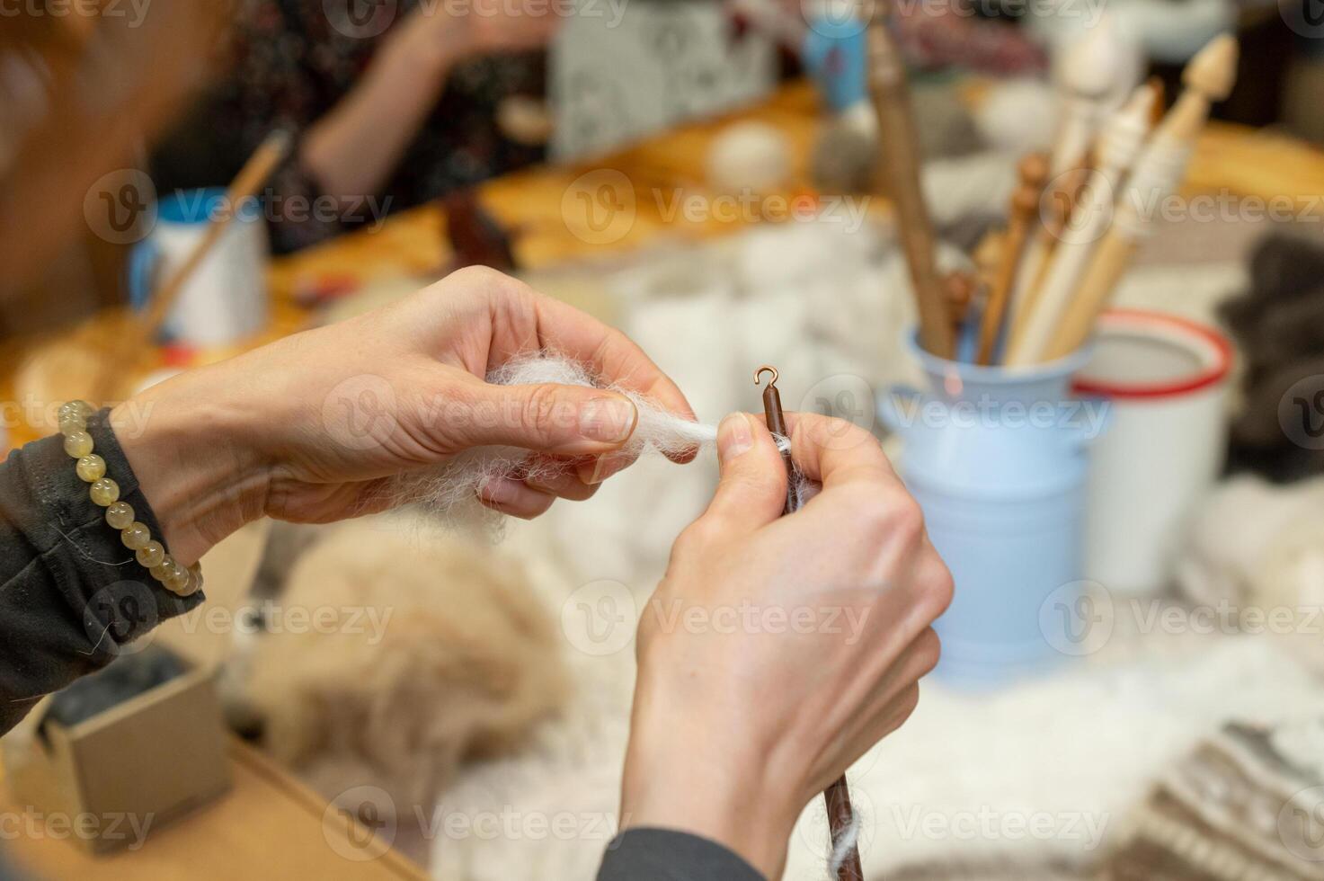 Caucasian female adult felting wool with craft tools at workshop table photo