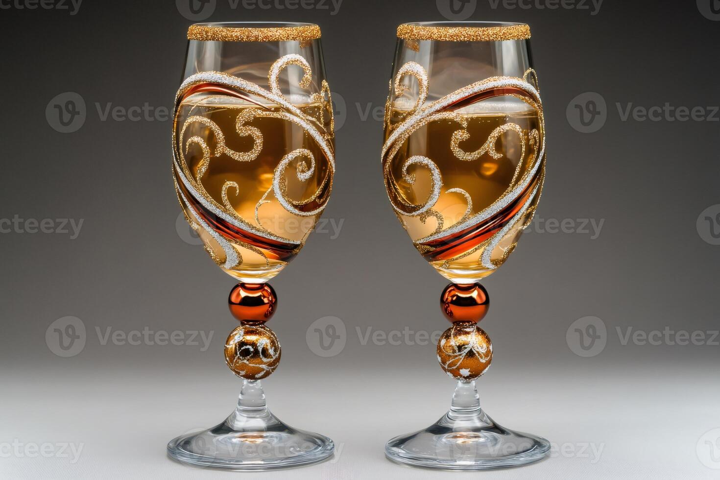 Two elegant wine glasses decorated with gold and copper ornaments containing white wine photo