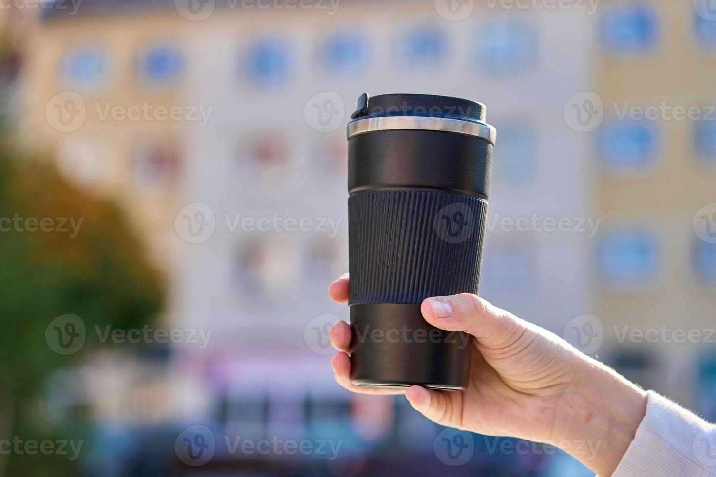 Woman holding reusable coffee cup outdoors in autumn photo