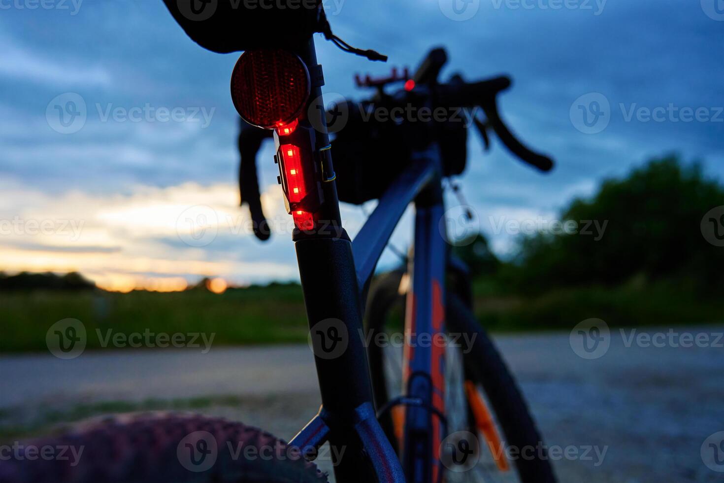 Glowing red bicycle tail light in twilight photo
