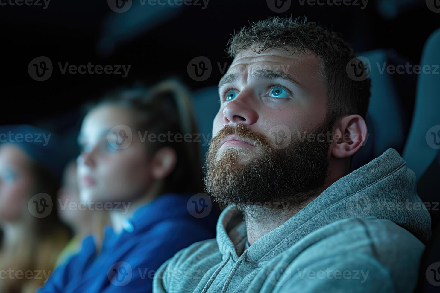 Group of people watching movie in the cinema. Focus on the empathetic man in the foreground photo