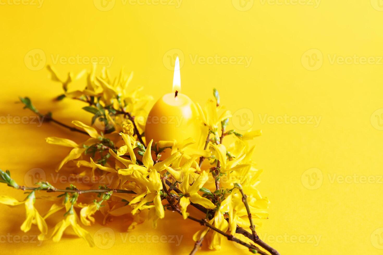 Yellow candle in the shape of egg and beautiful spring forsythia plant branches. photo