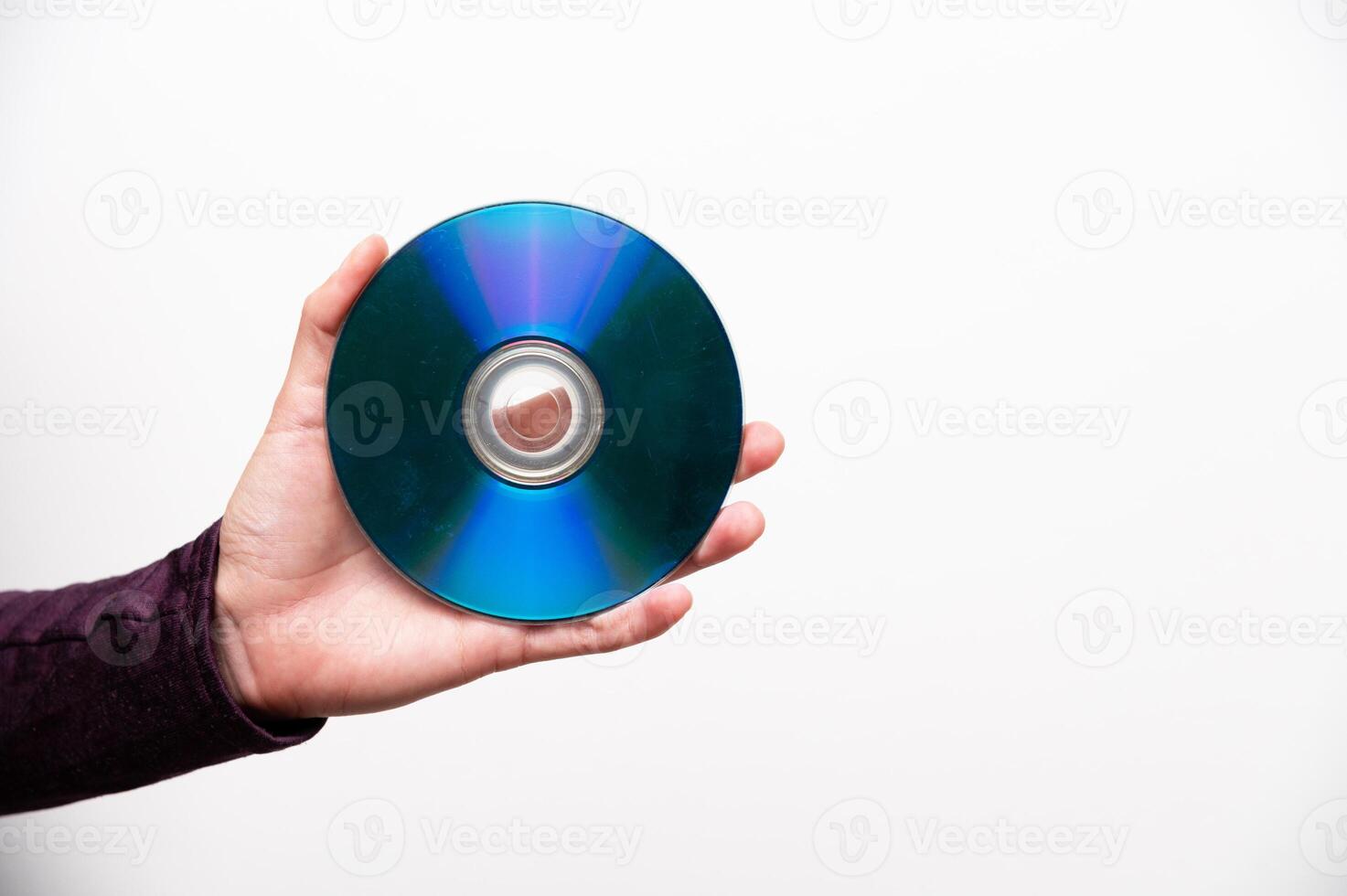 Compact disc in a woman's hand, rainbow side up, glittering on a white wall background photo