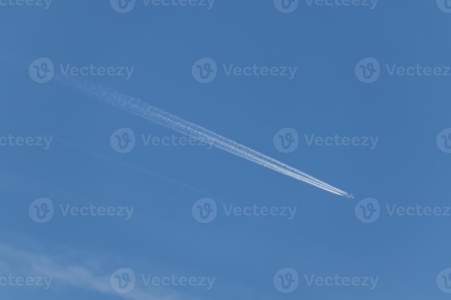 Contrails - one flying transport airplane with condensation trails in a blue sky photo