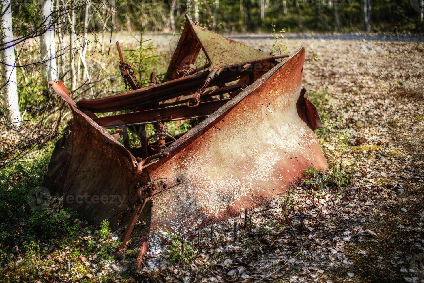 Historic rusty snow plow lying in the forest photo