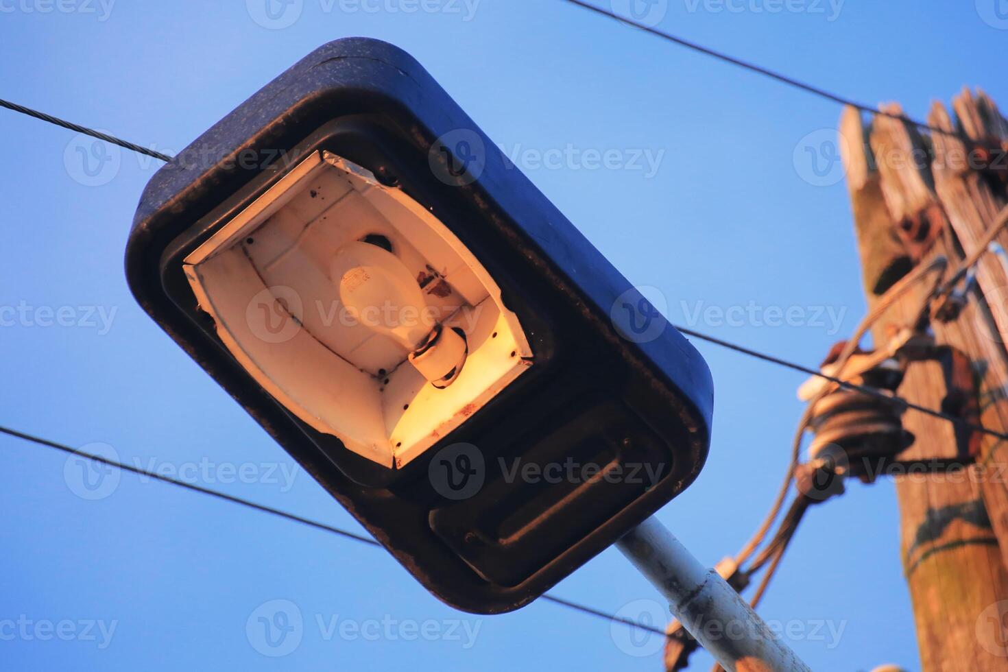 Old street lamp with power cables in warm evening light photo