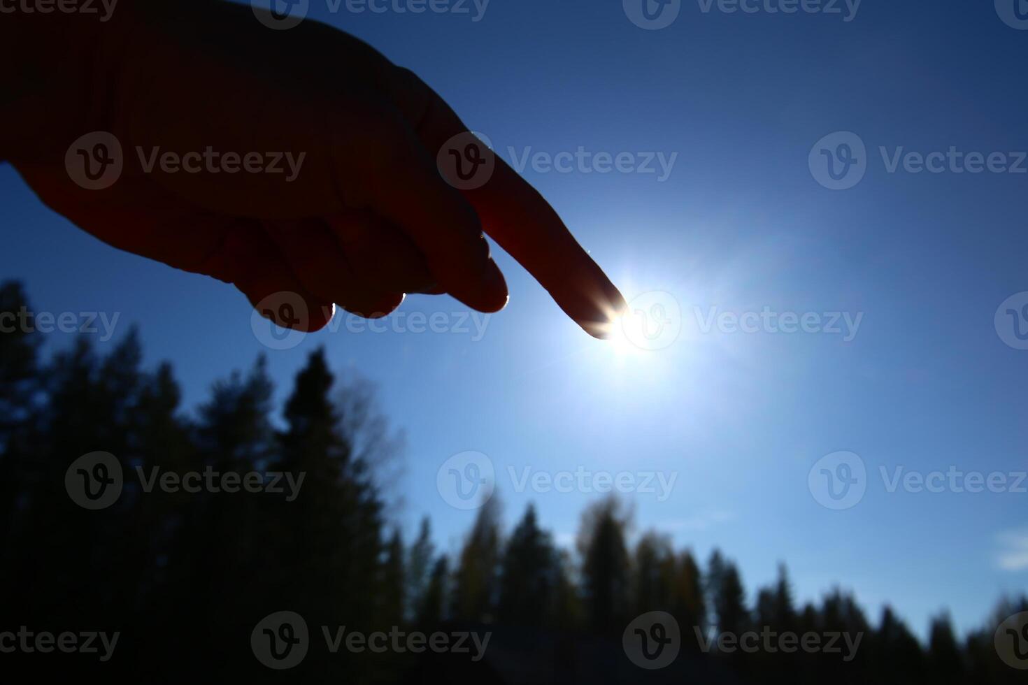 Pointing at the sun on a clear blue sky photo