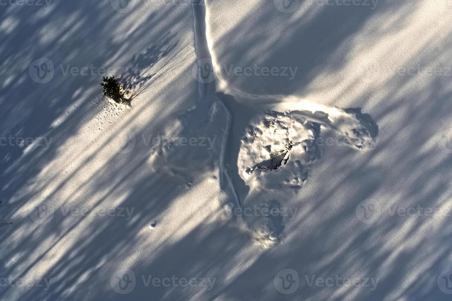 Conceptual aerial shot of tracks in the snow with diagonal shadows photo