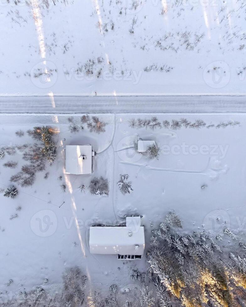 Drone shot directly downward snow covered group of houses with patches of sunlight photo