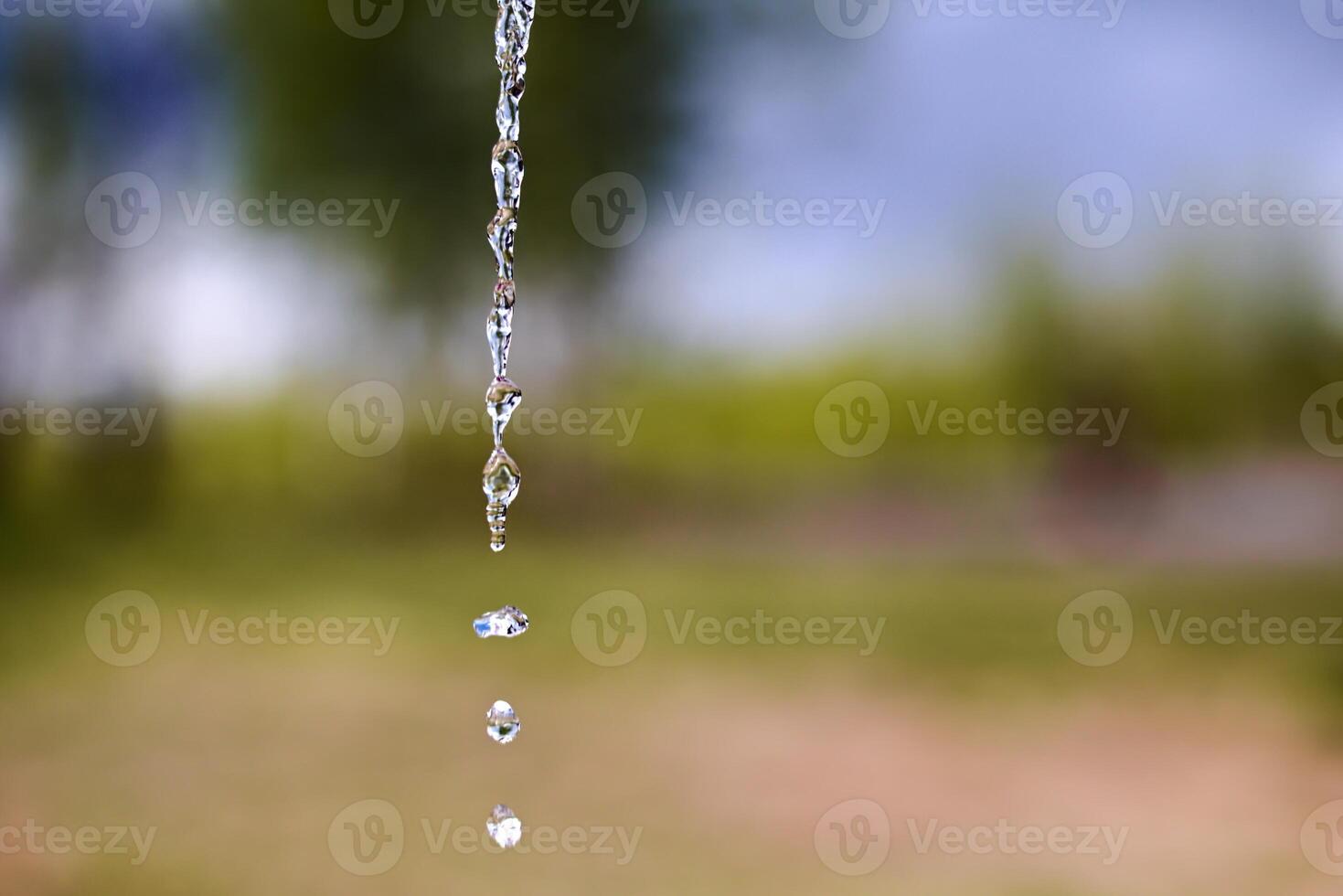 Fresh water drops falling in front of blurred natural background photo