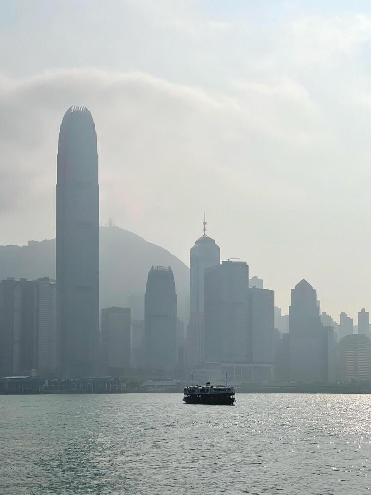 Silhouette of Hong Kong cityscape, commercial residential buildings and star ferry tourist ship photo