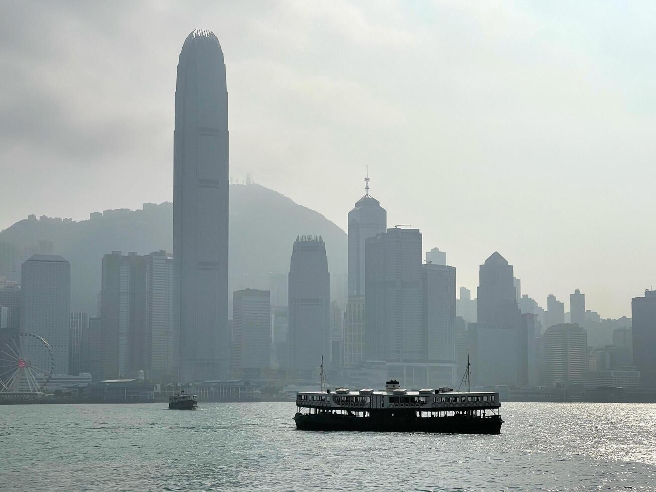 Silhouette of Hong Kong cityscape, commercial residential buildings and star ferry tourist ship photo