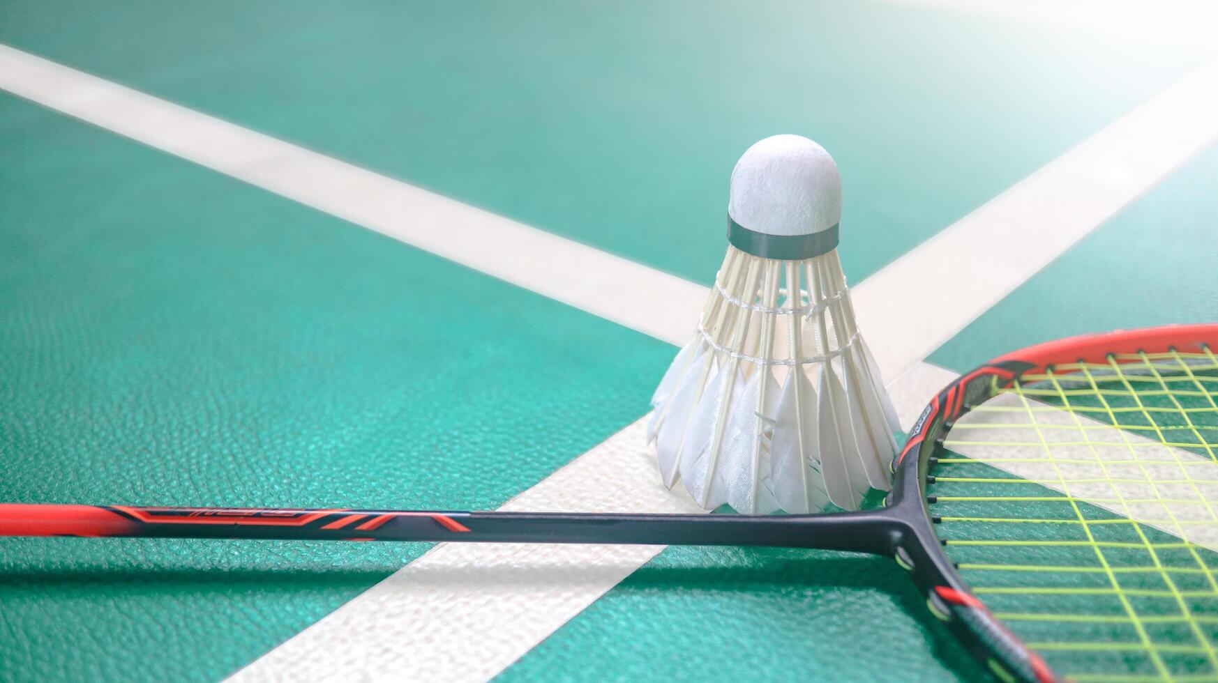White badminton shuttlecocks and badminton rackets on green floor indoor badminton court. Concept for badminton competition and its lovers. photo