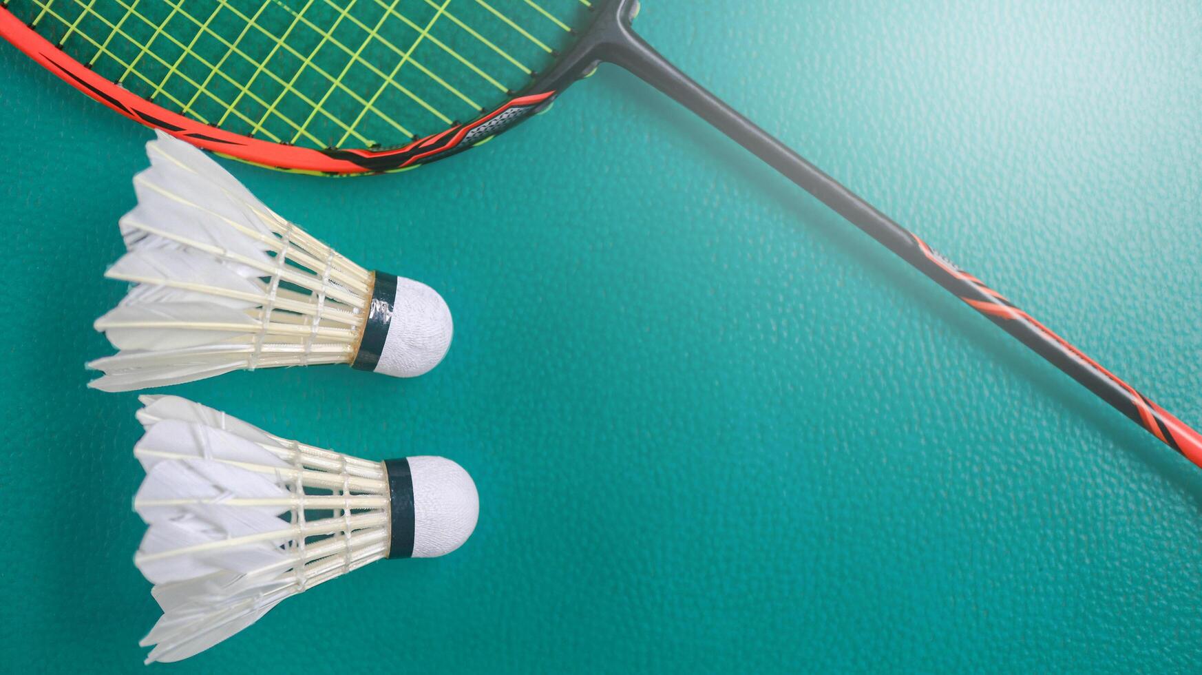 White badminton shuttlecocks and badminton rackets on green floor indoor badminton court. Concept for badminton competition and its lovers. photo