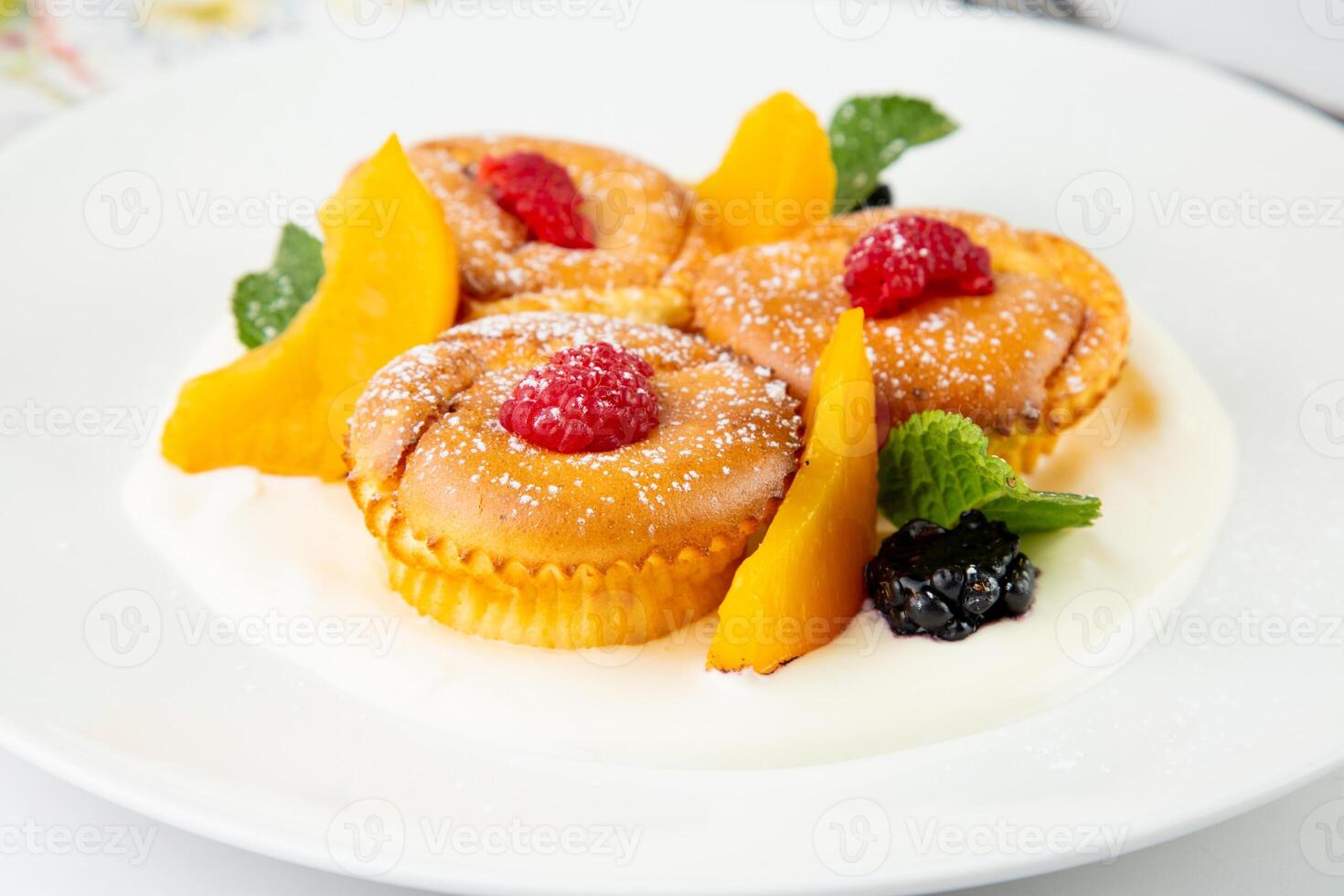 muffins with peach, raspberry, black berry and mint covered with powdered sugar, side view photo