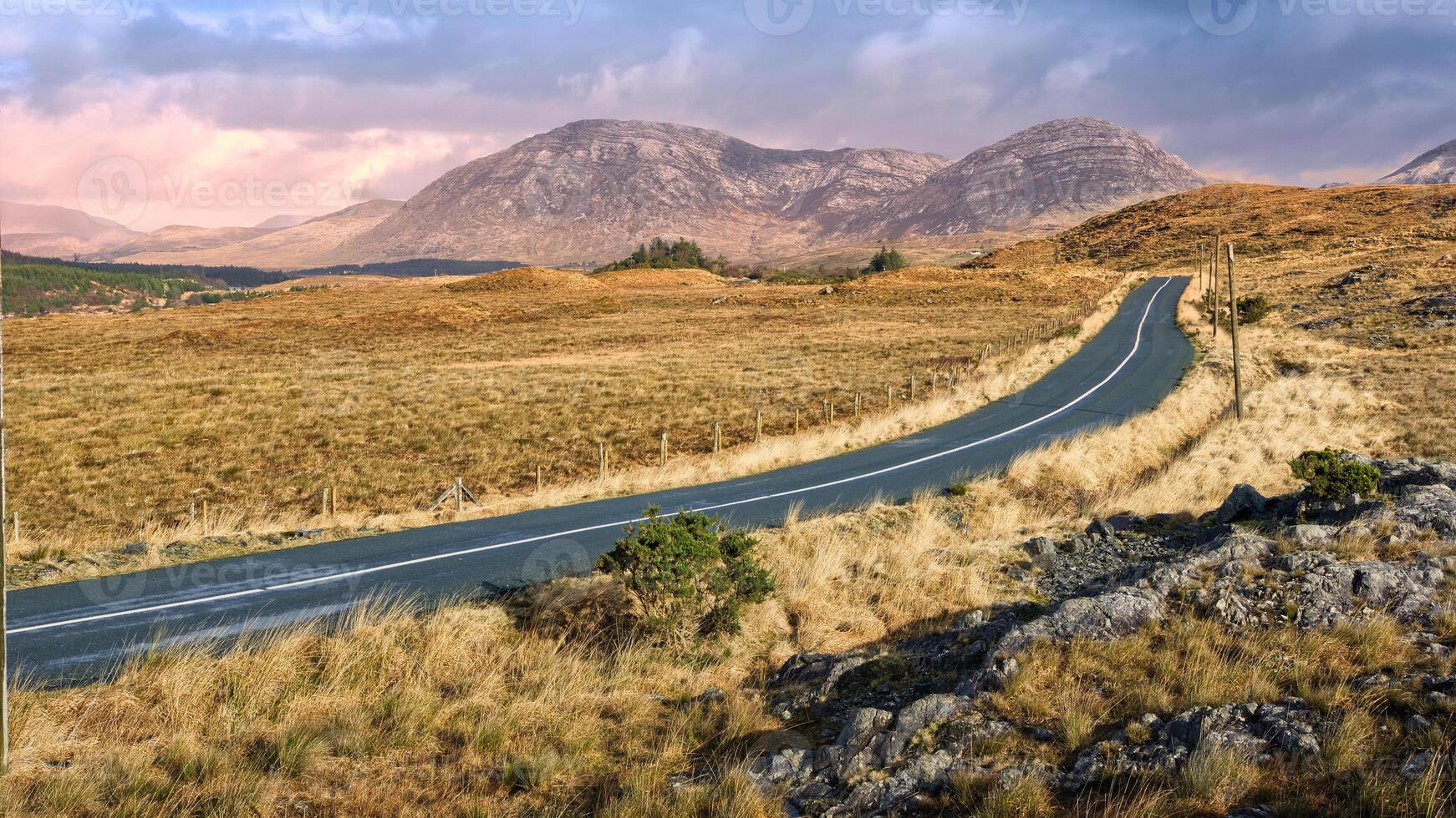 Beautiful landscape scenery, empty road trough nature with mountains in background at Connemara national park, Galway, Ireland photo