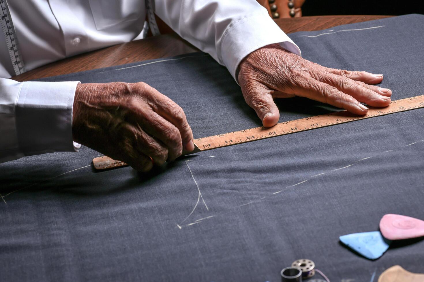 A tailor cutting a cloth according to the tradition of tailors. The dressmaker uses perfectly needle and thread to sew traditional concept, sewing photo