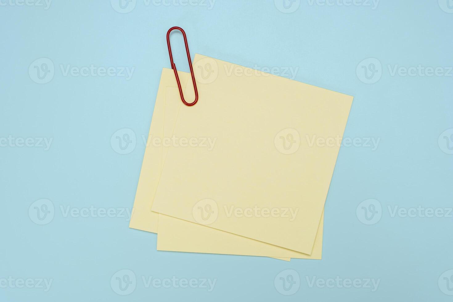 Blank post it note with green paper clip isolated on blue. Sticky notes texture pin memo reminder. photo