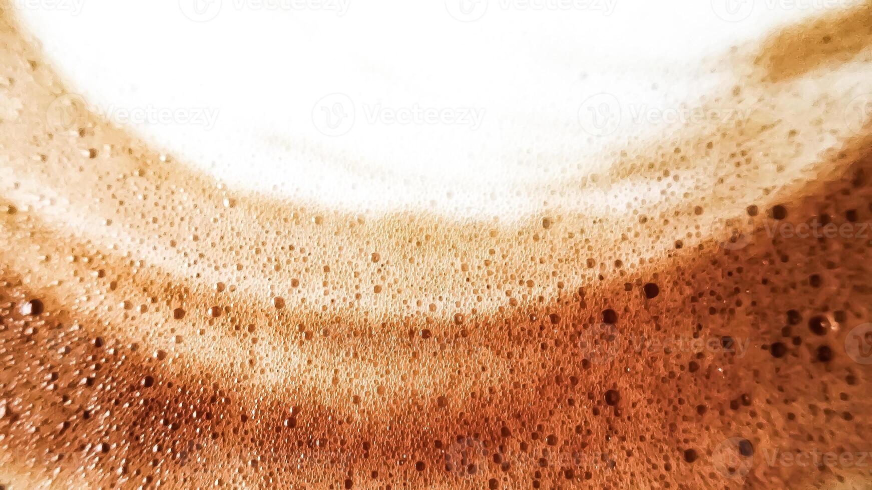 High-angle full-frame shot of coffee and milk swirling together, featuring frothy foam bubbles and creating a captivating abstract pattern. photo