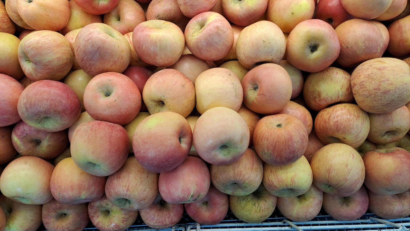 Pile of fresh apples with yellow and red skin, neatly arranged in a supermarket photo