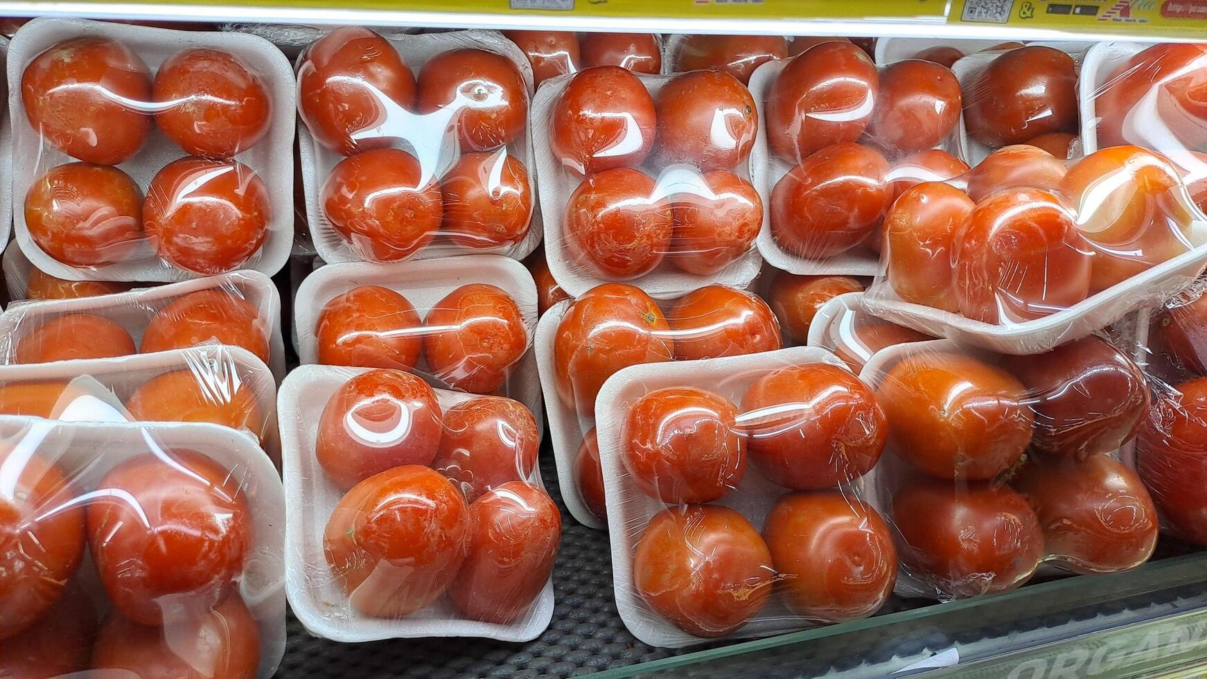 an arrangement of fresh red tomatoes wrapped in plastic, neatly arranged in a supermarket photo