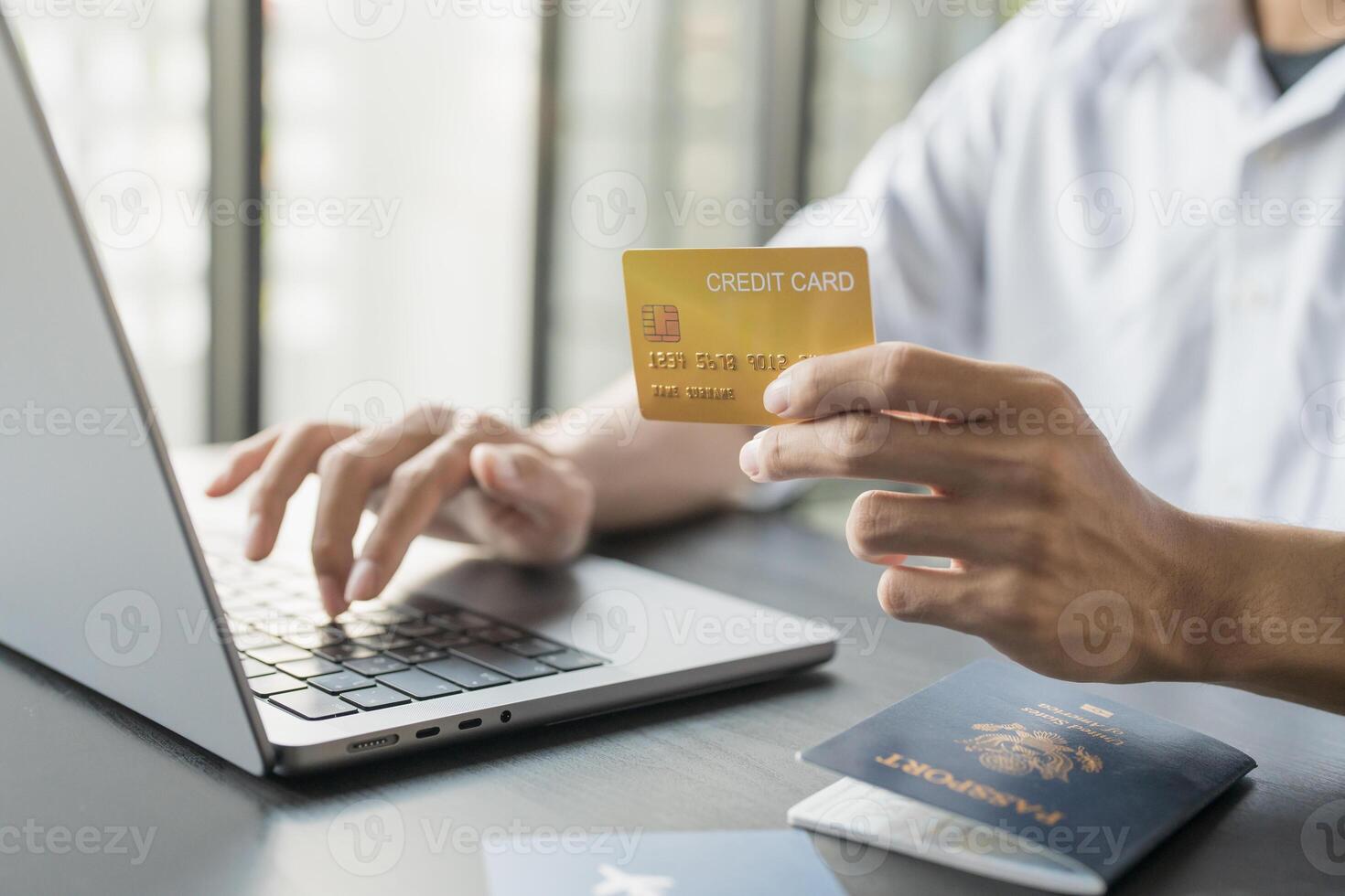 Hand Man Online booking and buying plane tickets using laptop phone and credit card Planning trip travel vacation with passport and ticket photo