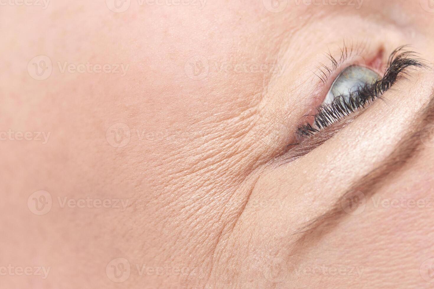 Close up of caucasian female mature eye with detailed wrinkles and expression lines. photo