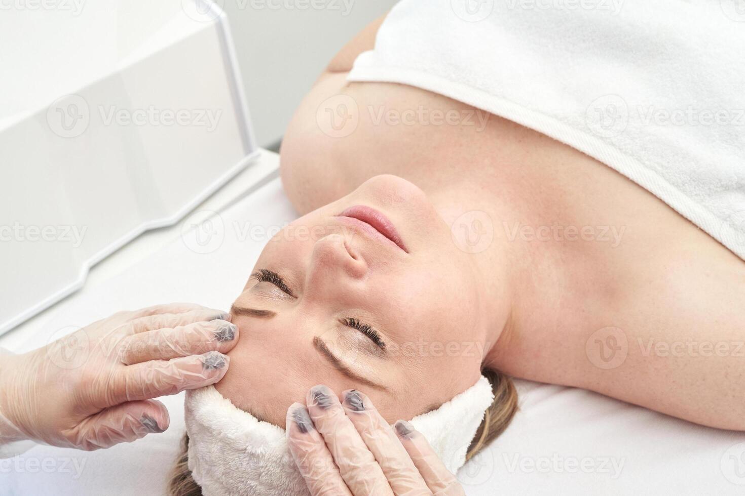 Caucasian female receiving facial massage at spa relaxation treatment session. photo