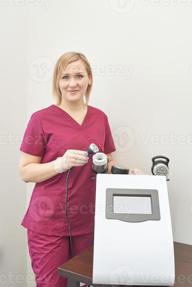 Female caucasian adult in burgundy scrubs operating medical equipment in clinical setting. photo