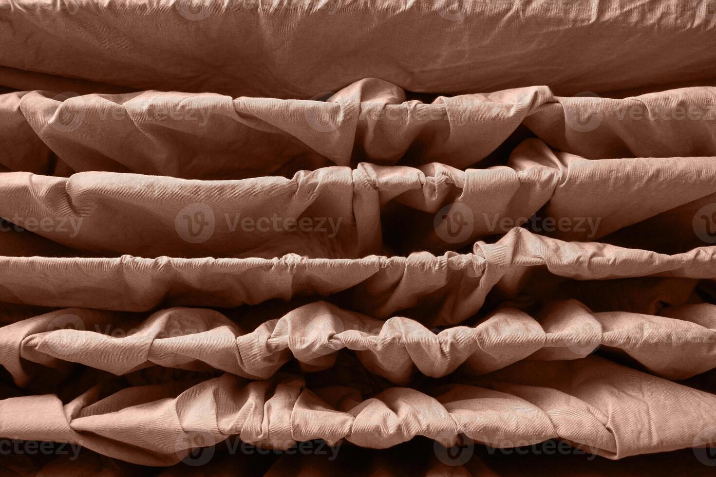 Abstract brown fabric texture with wavy layers and folds creating symmetrical patterns. photo