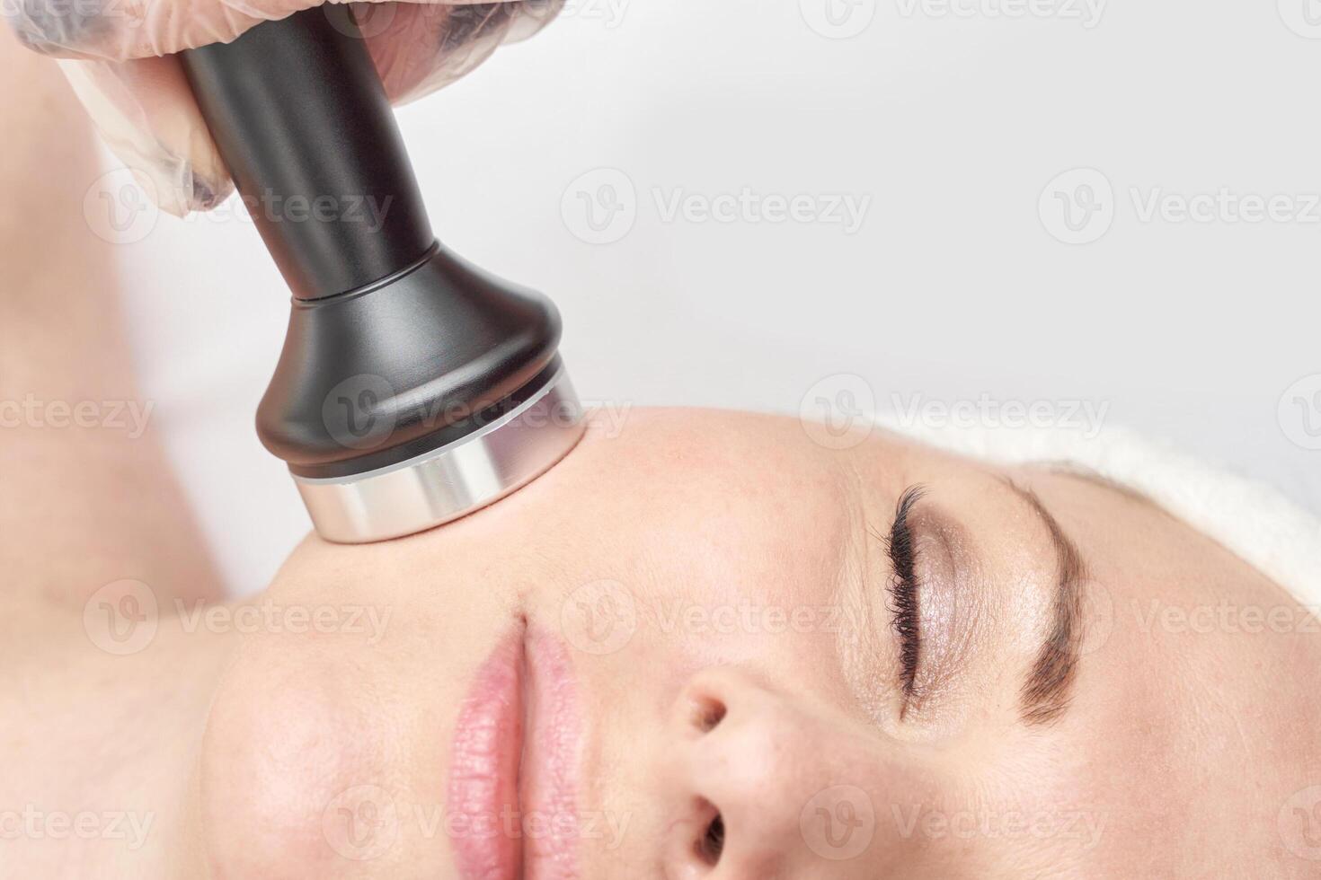 Caucasian female undergoing facial treatment with beauty device for skin rejuvenation and care. photo