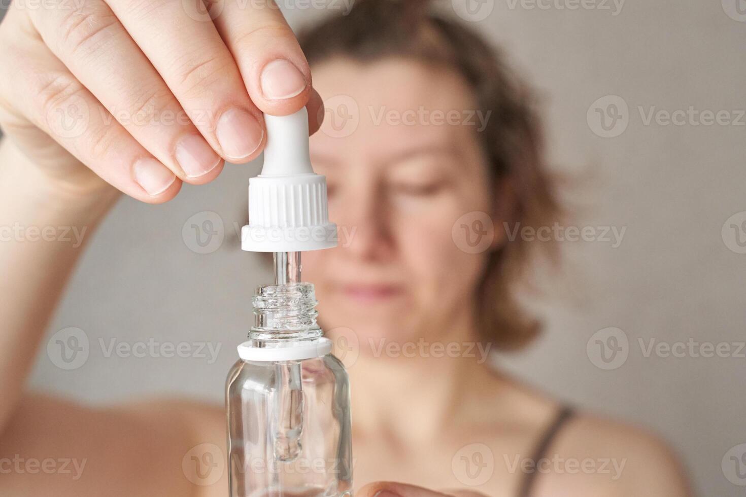 Caucasian female adult using skincare serum with dropper for facial routine at home. photo