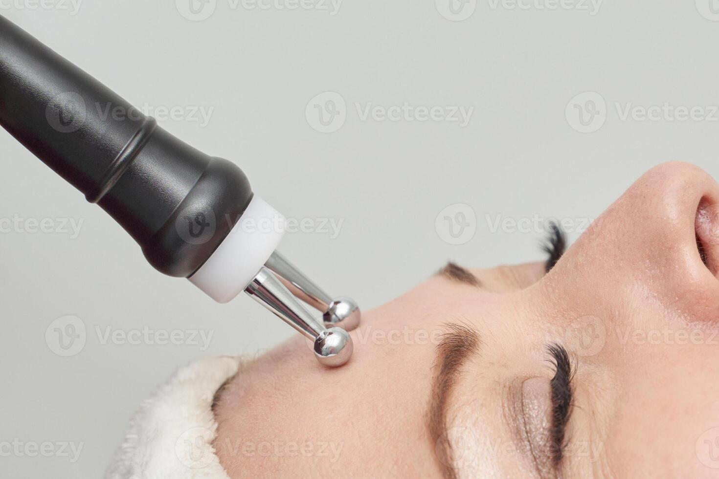 Close up of microcurrent facial treatment on caucasian female young adult with electrotherapy device. photo